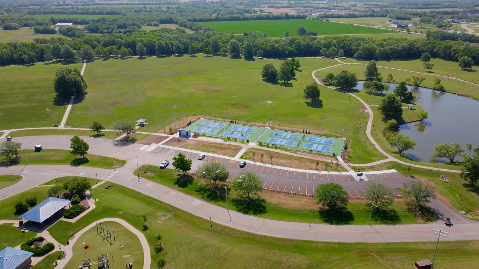 Aerial view of a Derby park with courts, a playground, and ponds